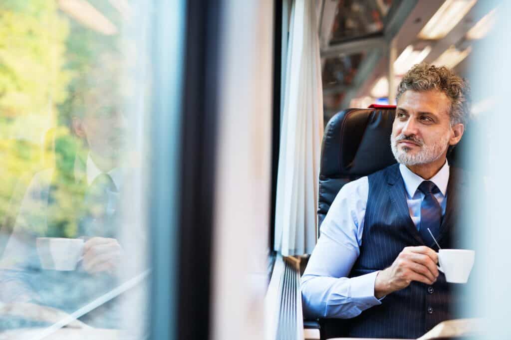 Mature businessman with coffee travelling by train.