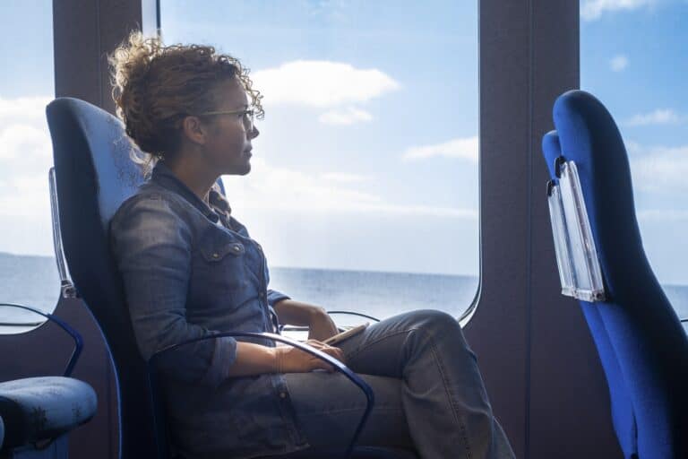 One woman traveling alone inside a ferry cruise with ocean and blue sky view. Concept of transport