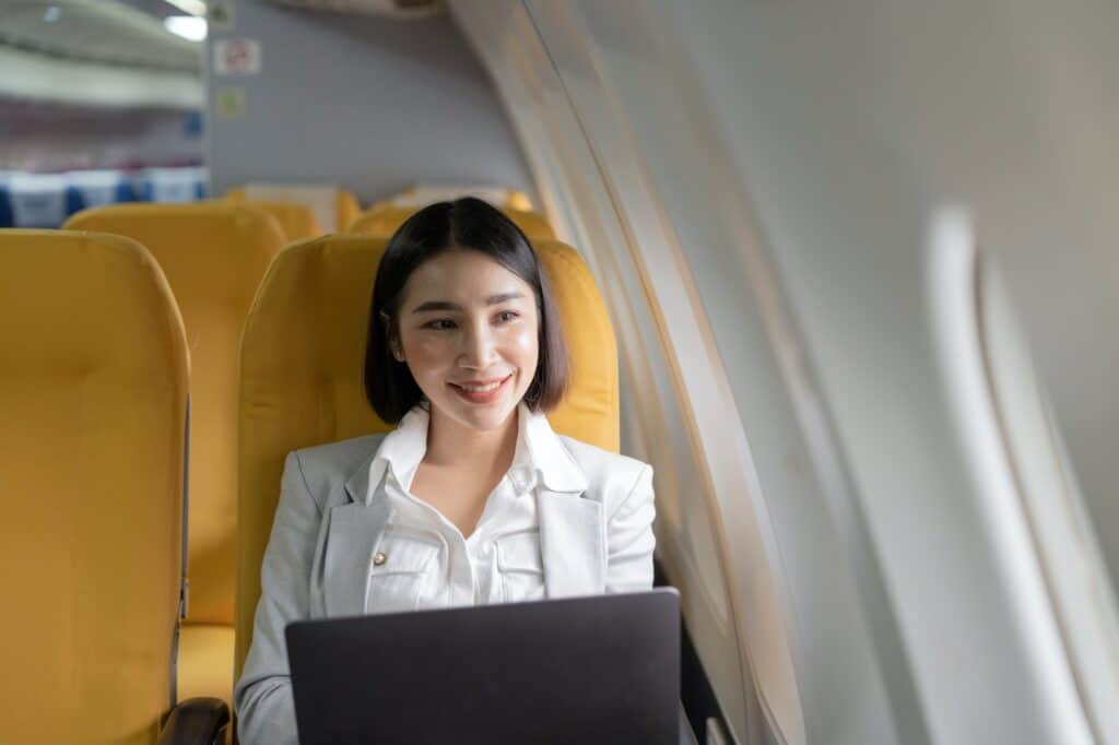 Traveling and technology. Flying at first class. Pretty young businees asian woman working on