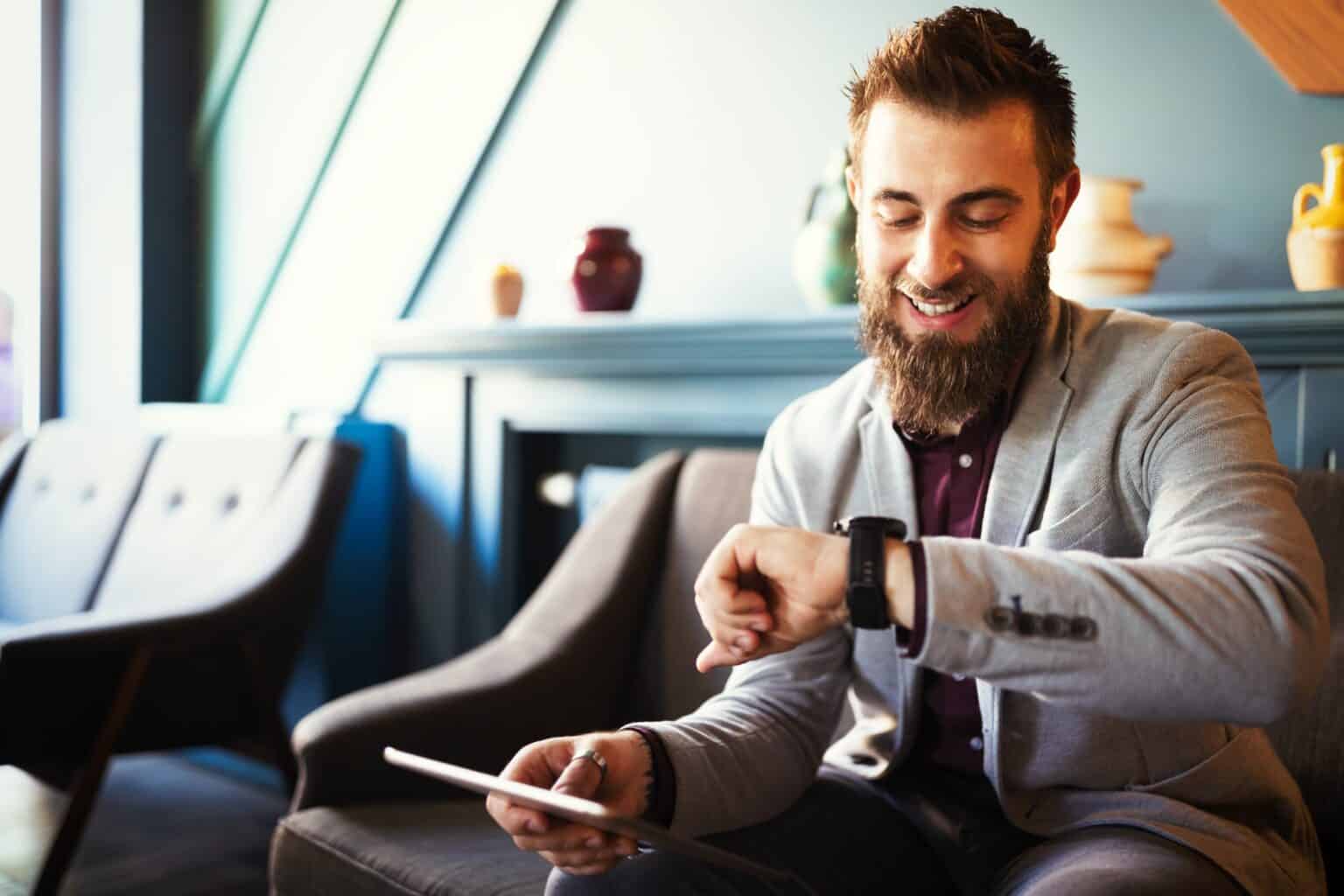Business and time management concept. Happy business man looking at wrist watch