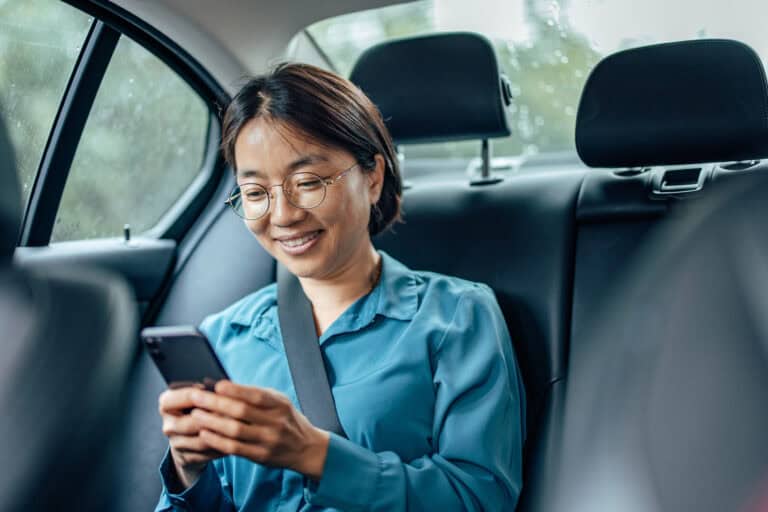 Person smiling while using a phone in car